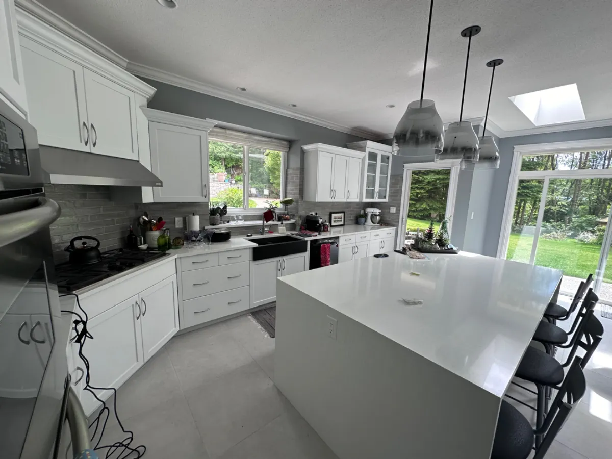 Renovated Anmore kitchen with white cabinets, grey backsplash and porcelain tile