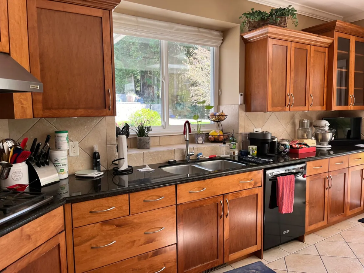 Kitchen sink wall before renovation with cherry cabinets and black granite