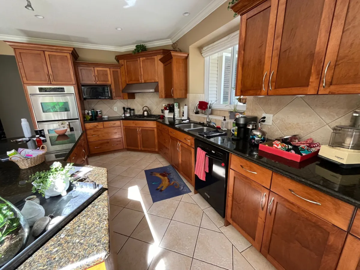 Kitchen before renovation showing stove area with cherry cabinets and double wall oven