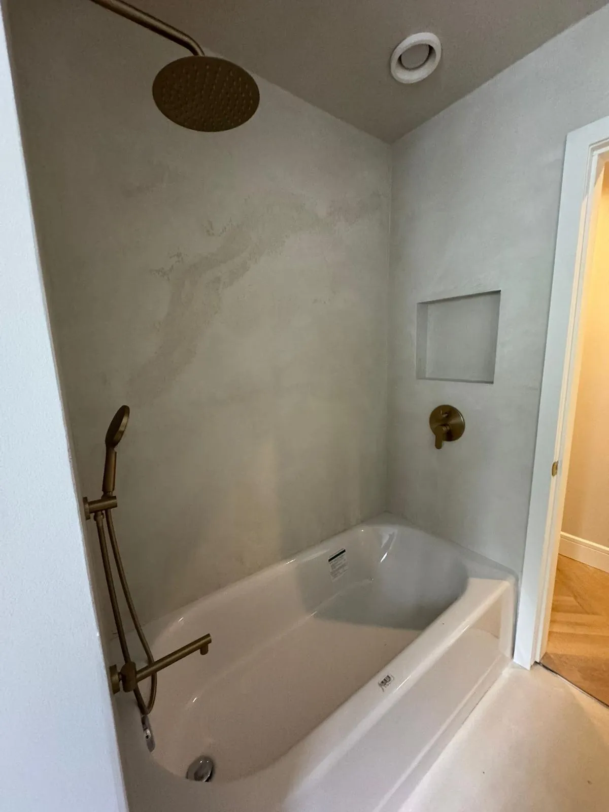 Renovated Burnaby main bathroom with modern tub, microcement walls and brass rain shower