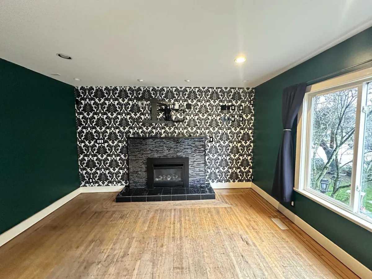 Living room before renovation with dark green walls and patterned wallpaper