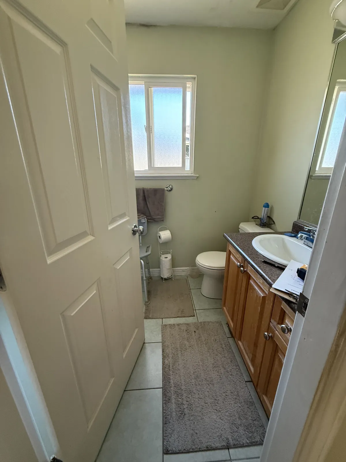 Bathroom before renovation with oak vanity, old tile floor and dated fixtures