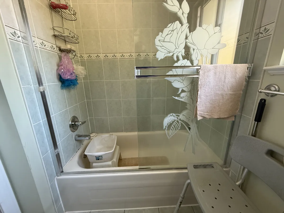 Old bathtub-shower combo with dated tile surround and etched glass doors