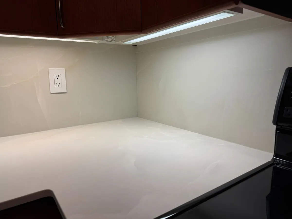 Close-up of completed quartz countertop and backsplash under cabinet lighting